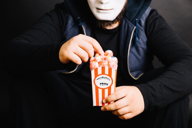 Ernte Mann in Maske essen Popcorn