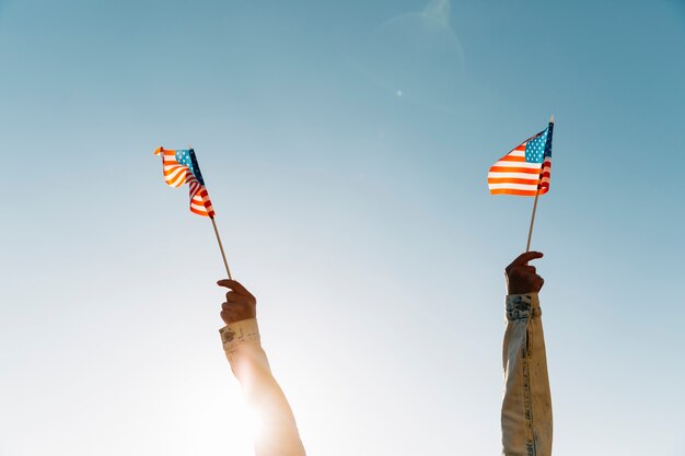 Erntefrau, die amerikanische Flaggen gegen blauen Himmel hält