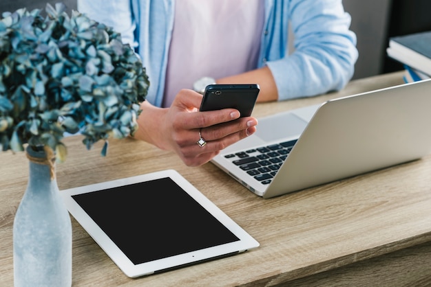 Erntefrau, die Smartphone im Büro durchstöbert