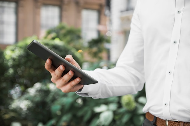 Erntegeschäftsmann, der Tablette auf Straße durchstöbert