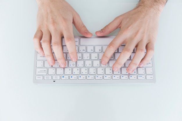 Kostenloses Foto ernten sie die hände, die auf kleiner tastatur schreiben