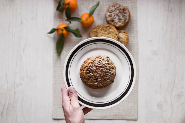 Ernten Sie die Hand, die Brötchen auf Platte hält