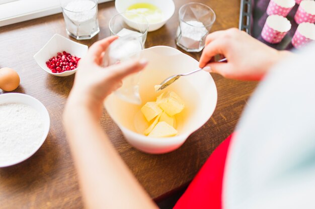 Ernten Sie die Person, die Butter in Schüssel setzt