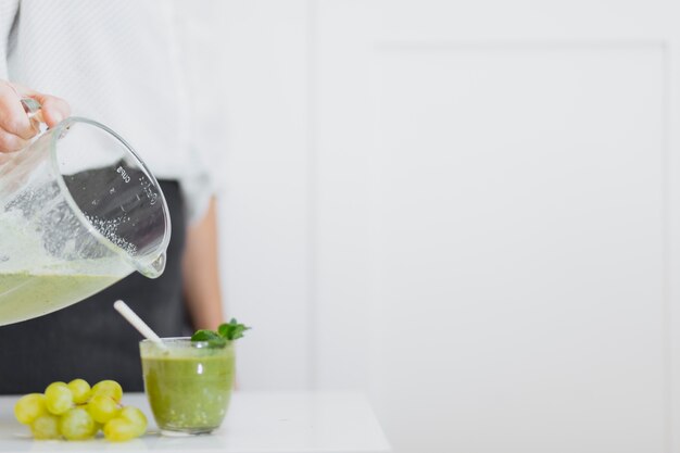 Ernten Sie die Person, die grünen Smoothie zum Glas gießt