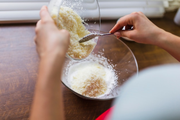 Ernten Sie die Person, die zerrissene Kokosnuss Butter hinzufügt