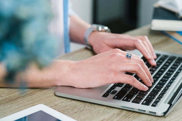 Ernten Sie Hände unter Verwendung des Laptops im Büro