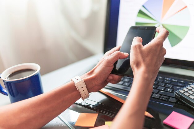 Ernten Sie Hände unter Verwendung des Smartphone im Büro