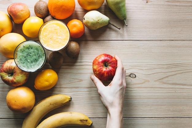 Ernten Sie Hand mit Apfel nahe Früchten und Smoothie