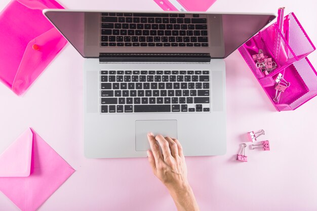 Ernten Sie Hand unter Verwendung des Laptops nahe Briefpapier