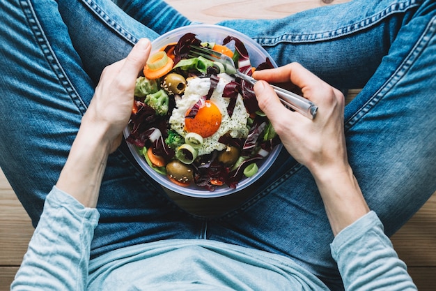 Erntenperson, die Salat mit Spiegelei isst