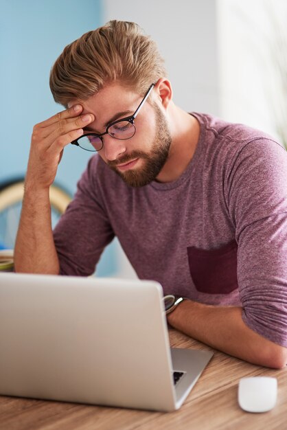 Erschöpfter Mann über dem Laptop