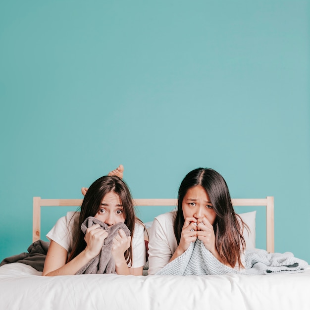 Erschrockene Frauen, die auf Bett liegen