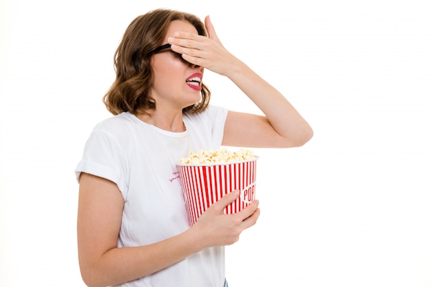 Erschrockene kaukasische Frau, die Popcorn-Film hält.