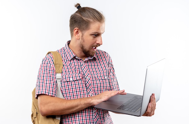 Erschrockener junger Kerl Student mit Rucksack benutzte Laptop isoliert auf weißer Wand