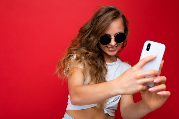 Erstaunlich schöne lächelnde junge frau, die ein handy hält und ein selfie-foto mit dem smartphone macht