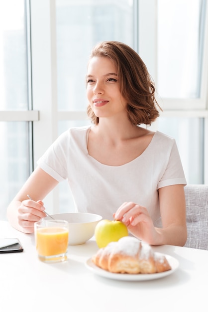 Erstaunliche Frau, die drinnen am Tisch mit Saft sitzt