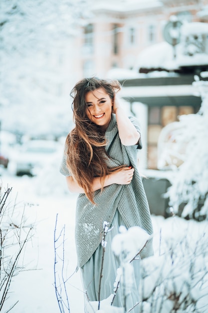 Kostenloses Foto erstaunliche frau in einer strickjacke und in einem hellen kleid steht im garten unter büschen