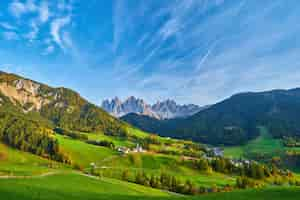 Kostenloses Foto erstaunliche herbstlandschaft im dorf santa maddalena mit bunten kirchenbäumen und wiesen unter aufgehenden sonnenstrahlen dolomiten italien