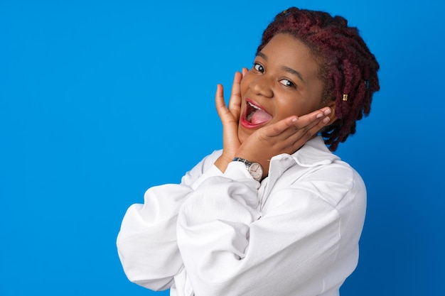Erstaunt überraschte afroamerikanische Frau vor blauem Studiohintergrund
