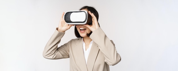 Erstaunte Geschäftsfrau im Anzug mit Virtual-Reality-Brille, die im vr-Headset über weißem Hintergrund erstaunt aussieht