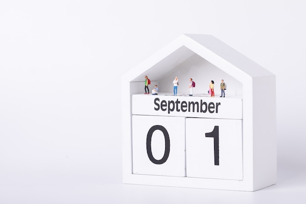 Erster Schultag. Figuren von Studenten, die auf einem Kalender stehen, der den ersten September darstellt