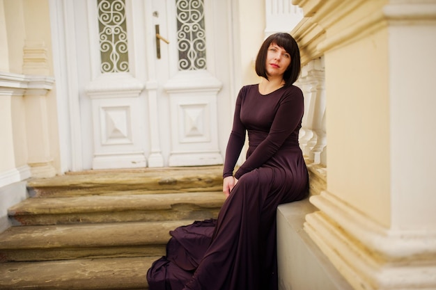 Erwachsene brünette Frau im violetten Kleid Hintergrund altes Vintage-Haus mit Treppe