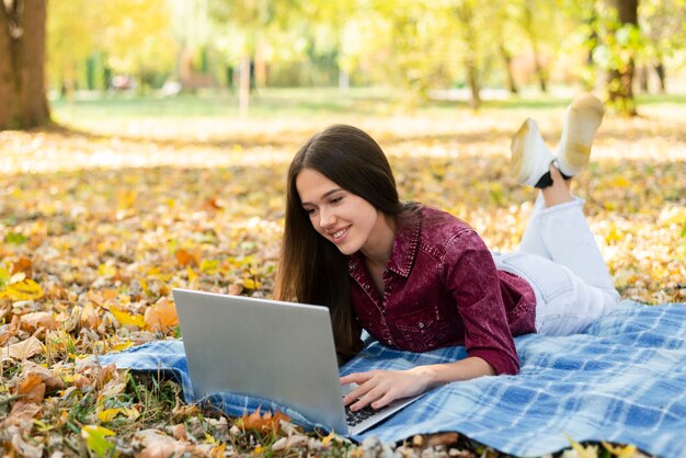 Erwachsene Frau, die draußen an Laptop arbeitet