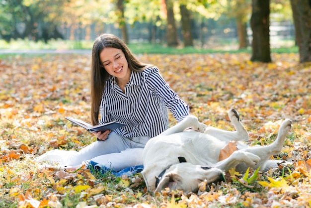 Erwachsene Frau, die ihren Hund im Park streichelt