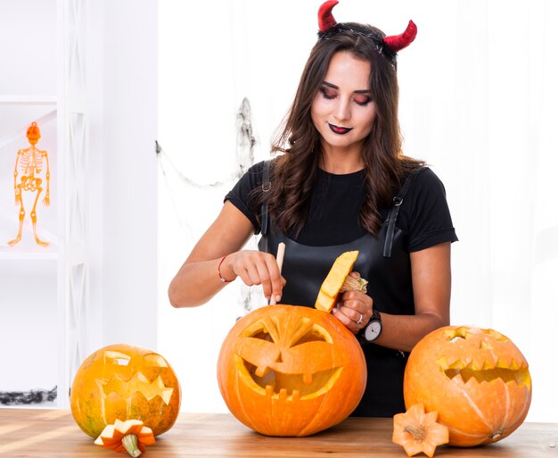 Erwachsene Frau, die Kürbise für Halloween schnitzt
