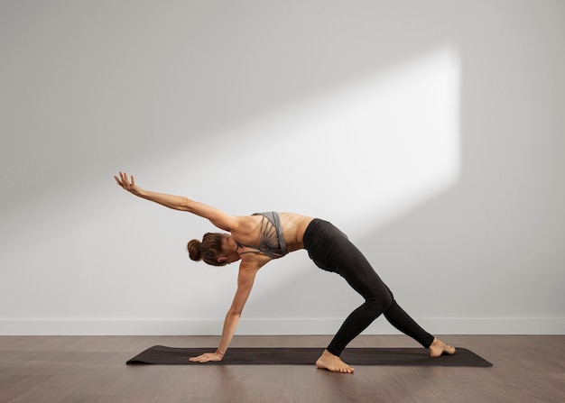 Kostenloses Foto erwachsene frau, die yoga zu hause macht