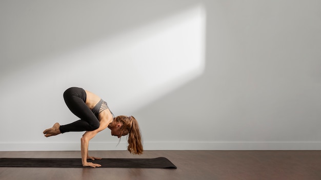 Erwachsene frau, die yoga zu hause macht
