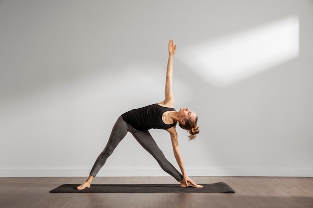 Erwachsene Frau, die Yoga zu Hause macht