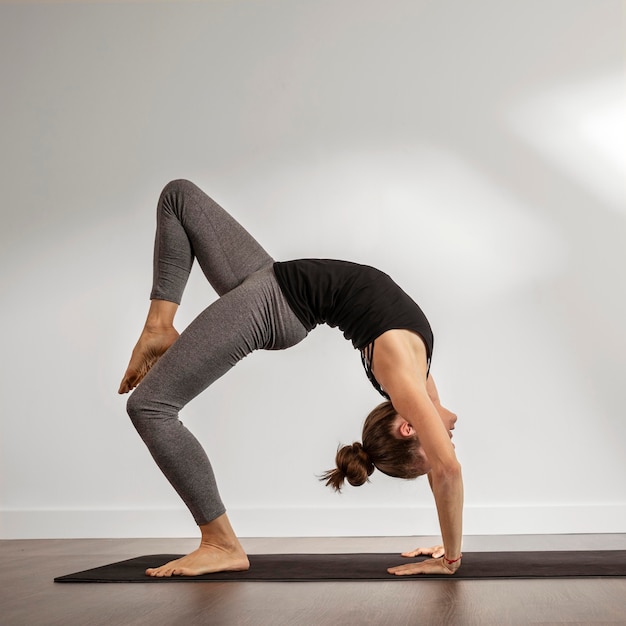 Erwachsene Frau, die Yoga zu Hause macht