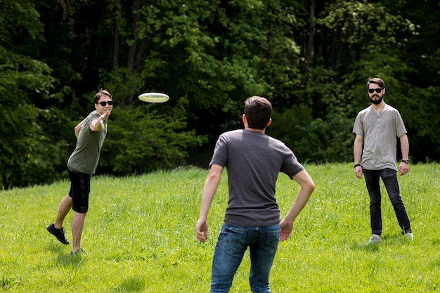 Kostenloses Foto erwachsene männer, die im park durch das spielen von frisbee stillstehen