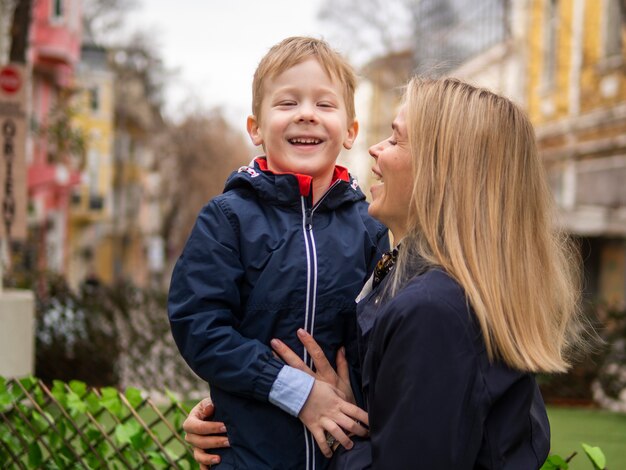 Erwachsene Mutter, die ihren Jungen draußen hält