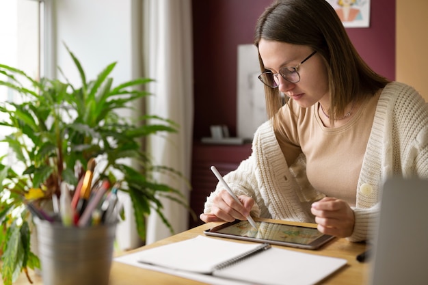 Kostenloses Foto erwachsene weibliche illustratorin, die an einem tablet-gerät arbeitet