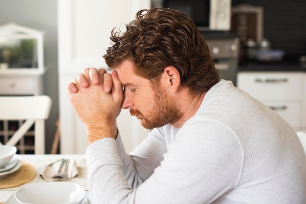 Erwachsener emotionaler Mann, der zu Hause betet