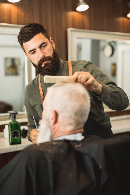 Erwachsener Friseur, der Kundenhaar am Friseursalon schneidet