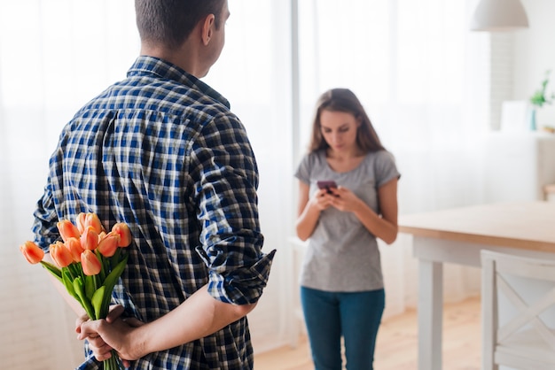 Erwachsener Mann, der Überraschung für Frau mit Telefon vorbereitet