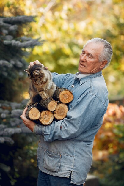 Erwachsener Mann, der Brennholz und eine Katze hält