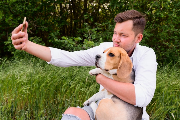 Erwachsener Mann, der ein Selfie mit niedlichem Hund nimmt