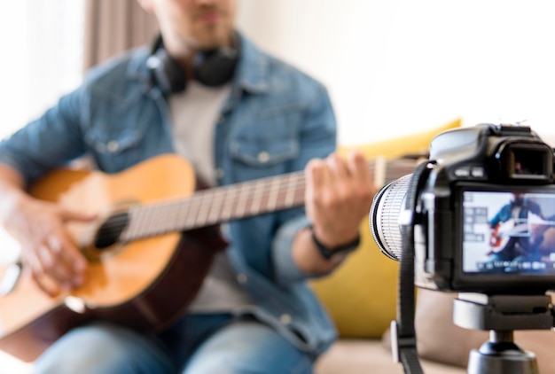 Erwachsener Mann, der sich aufnimmt, während er Gitarre spielt