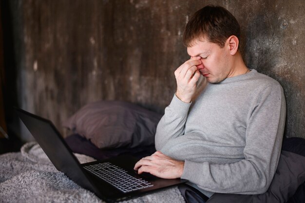 Erwachsener Mann, der von zu Hause auf Laptop arbeitet