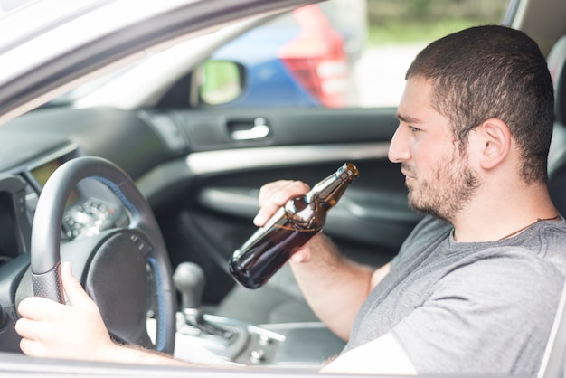 Erwachsener Mann mit Bier Auto fahren