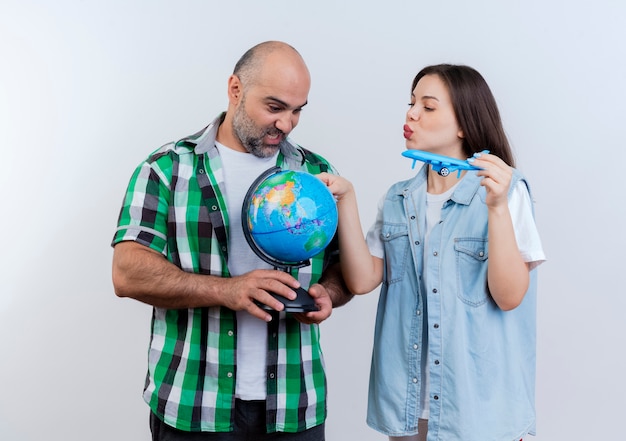Erwachsenes reisendes Paar beeindruckte Mann, der Globus und Frau hält Modellflugzeug, das Globus berührt und beide Globus betrachtet