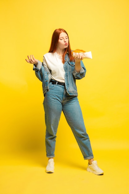 Es ist einfacher, Anhänger zu sein. Sie müssen nicht mit Essen fotografieren. Kaukasische Frau auf gelbem Hintergrund. Schönes weibliches rotes Haarmodell. Konzept der menschlichen Emotionen, Gesichtsausdruck, Verkauf, Anzeige.