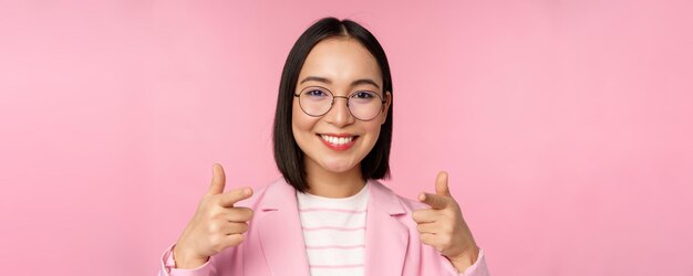 Es ist Ihnen herzlichen Glückwunsch, lächelnde asiatische Unternehmensfrau, CEO-Managerin in Anzug und Brille, die mit dem Finger zeigt