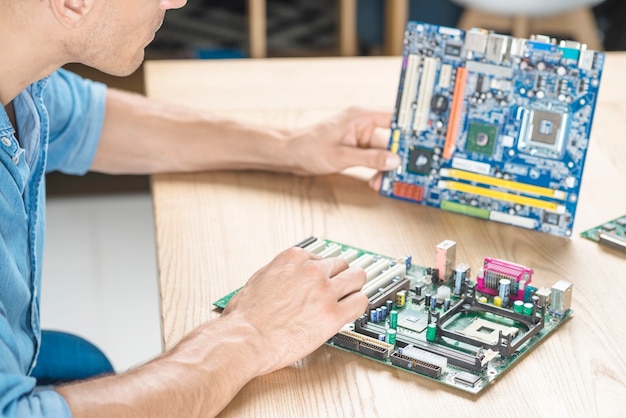 Es Techniker, der das Motherboard auf Holztisch aufrüstet