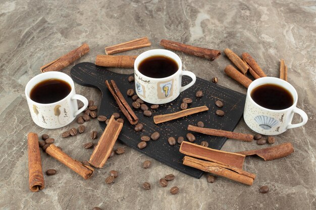 Espressokaffee, Zimtstangen und Kaffeebohnen auf Marmoroberfläche
