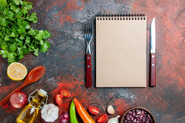 Esstisch mit einem Bündel grüner Ölflasche Knoblauch und Notizbuch auf gemischtem Farbtisch